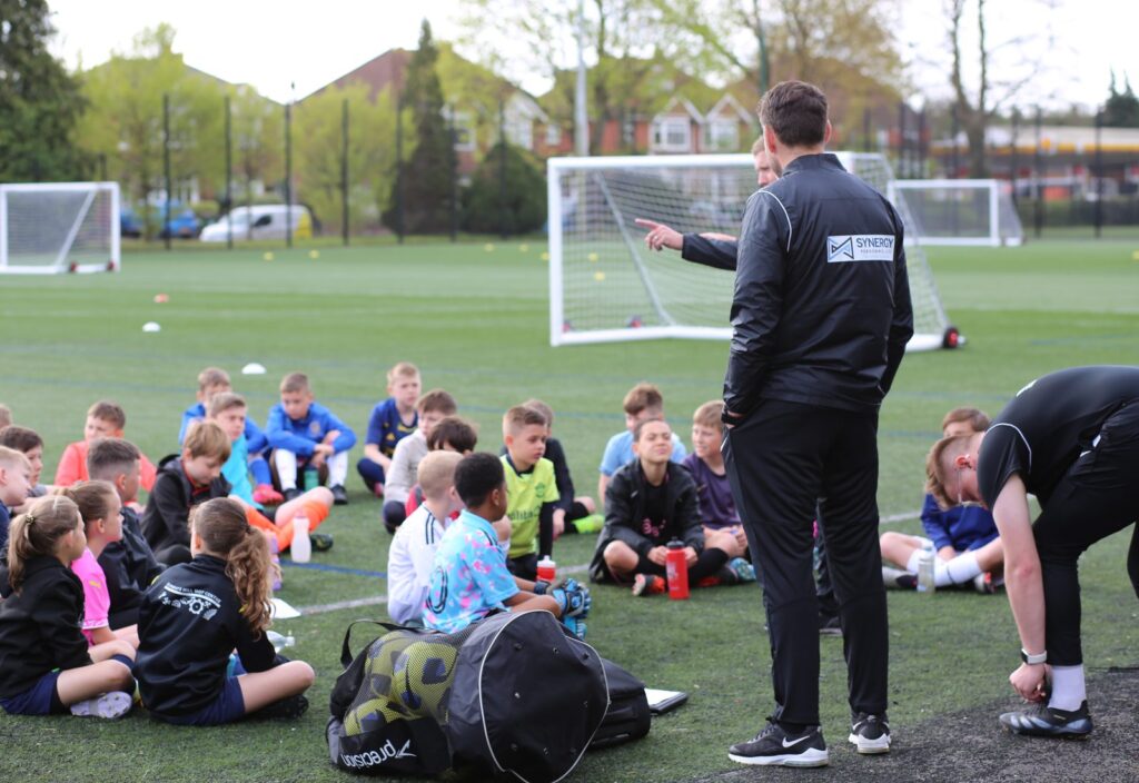 James Beattie talking to a group of young players on the pitch