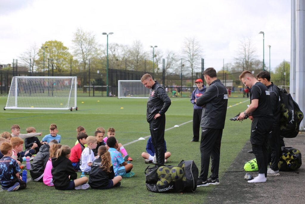 Coaches with players sitting on the pitch